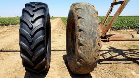 A brand new irrigation tire next to one that is heavily worn from use in the field.