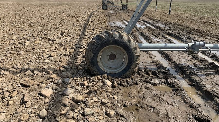 A tire navigating a rocky path next to a muddy, soft-soil field.