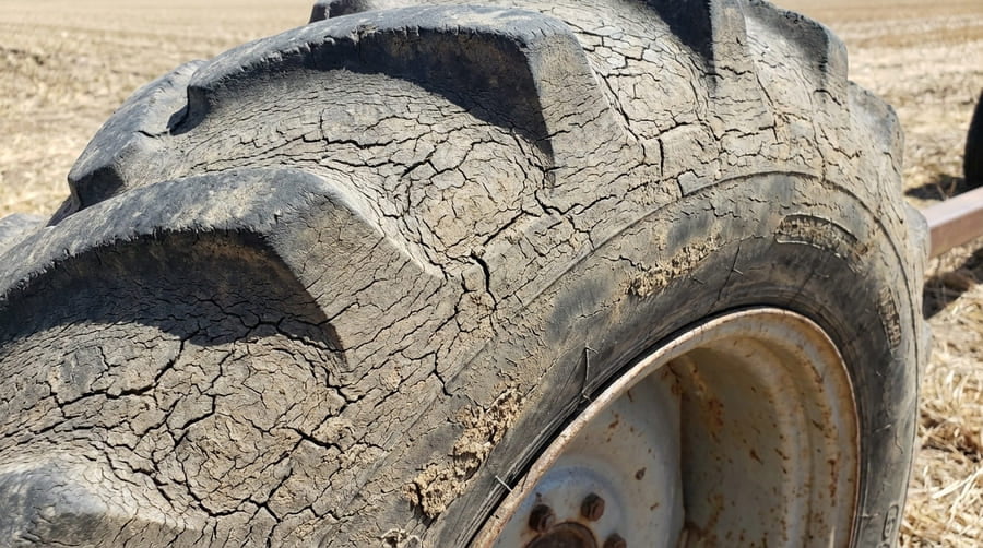 A close-up shot of a tire sidewall with severe cracking from sun exposure.
