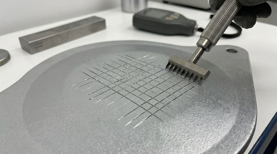 An image showing a cross-hatch adhesion test being performed on a galvanized surface, with no flaking.